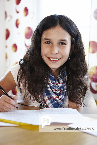 Porträt eines lächelnden Mädchens  das Hausaufgaben macht
