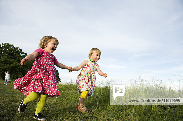 Two small girls running on meadow