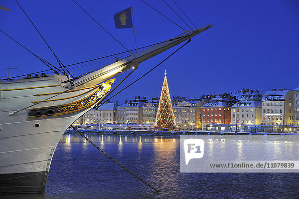 Boot mit beleuchtetem Weihnachtsbaum und Gebäuden im Hintergrund