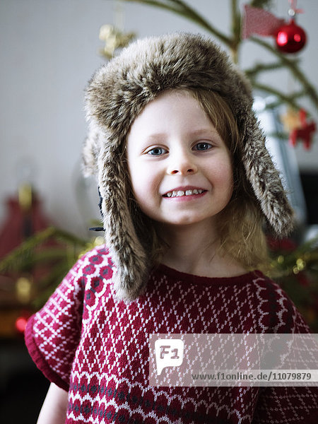 Portrait of girl wearing fur hat  christmas tree in background