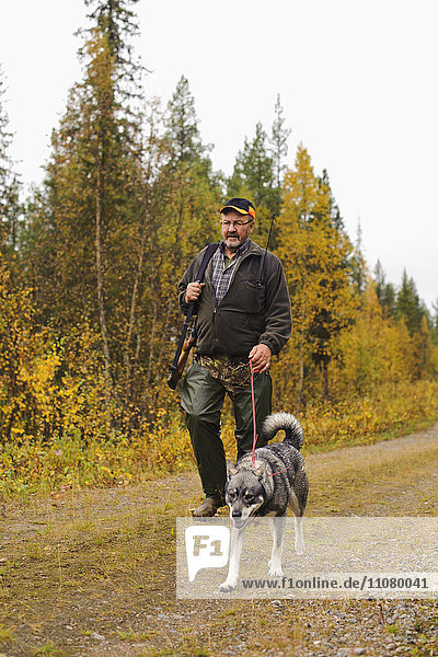 Mann geht mit Hund im Wald spazieren