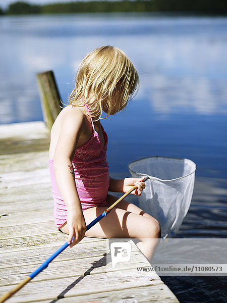 Girl sitting on jetty with fishing net
