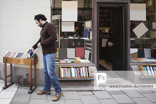Customer searching book while standing on sidewalk outside library