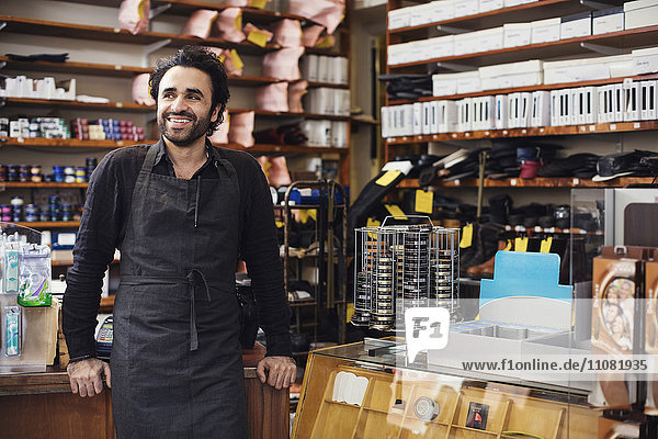 Smiling man standing in shoe repair store