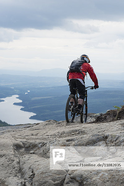 Rückansicht des Mountainbikers auf dem Felsen gegen den Himmel