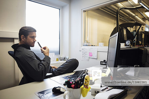 Zuversichtlicher männlicher Besitzer beim Blick auf den Computerbildschirm im Büro
