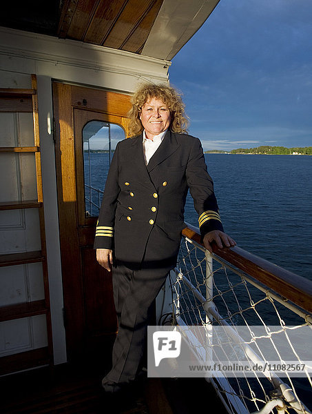Lächelnde Frau in Kapitänsuniform an Bord