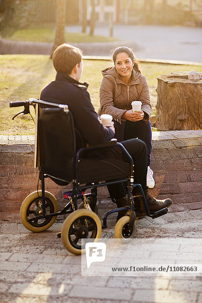 Junge Frau und Mann im Rollstuhl machen Kaffeepause