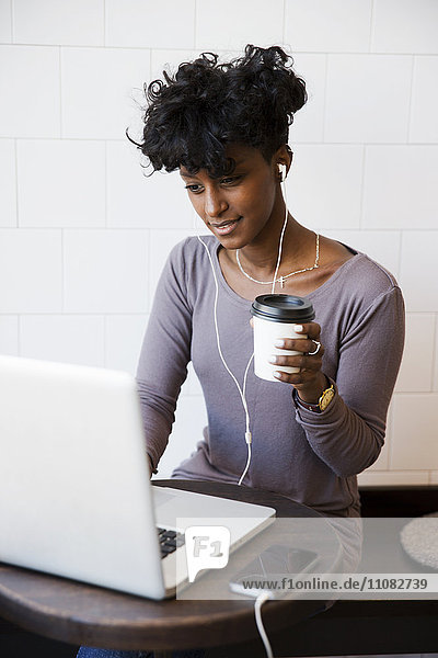 Junge Frau arbeitet an einem Laptop in einem Café  Stockholm  Schweden