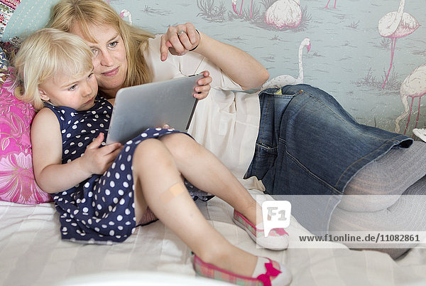 Mutter mit Kindern  die ein digitales Tablet benutzen