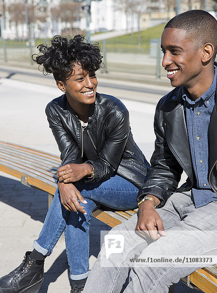 Smiling young couple sitting on bench