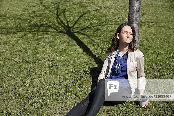 Junge Frau sitzt unter einem Baum  Stockholm  Schweden