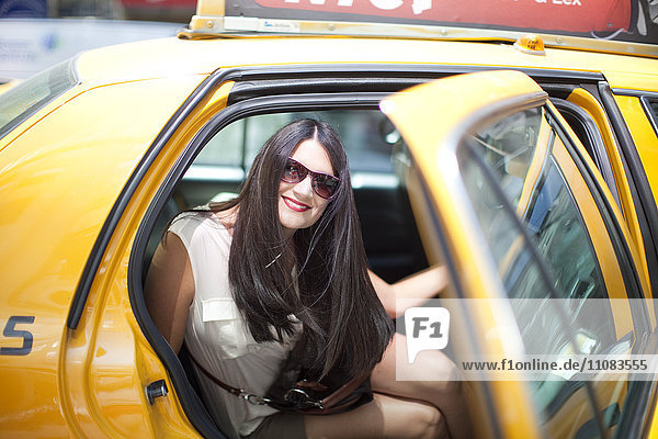 Lächelnde junge Frau in gelbem Taxi  New York City  USA