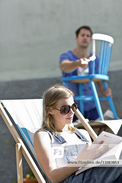 Junge Frau liest  Mann im Hintergrund malt  Stockholm  Schweden
