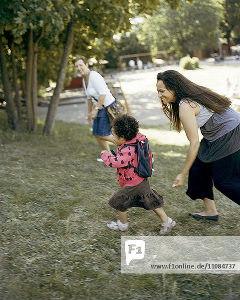 Mädchen mit Mutter läuft auf Rasen