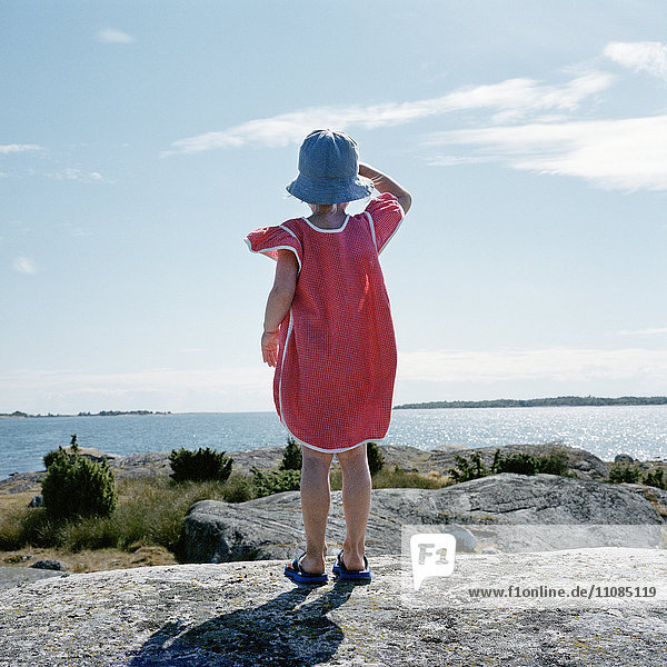 Mädchen steht auf einem Felsen und schaut auf das Meer  Schweden.