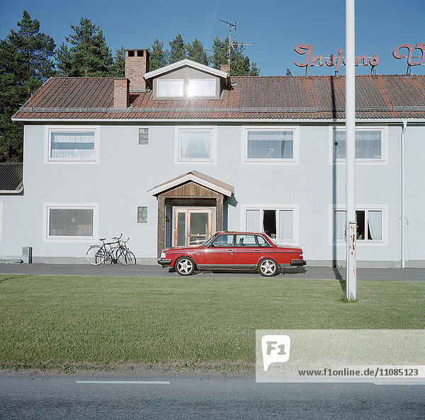 Ein roter Volvo vor einem weißen Haus  Schweden.