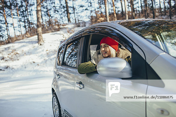 Happy young woman in car during winter