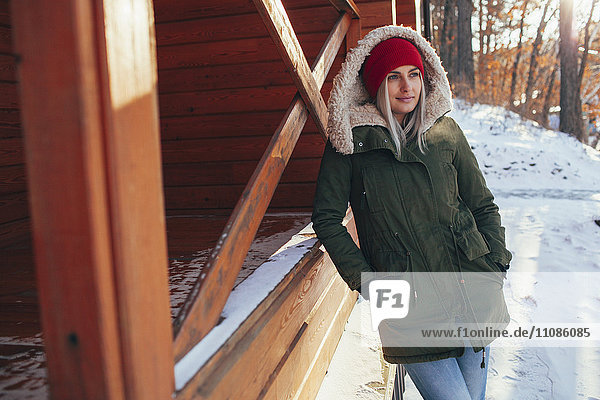 Young woman looking away while leaning on cabin