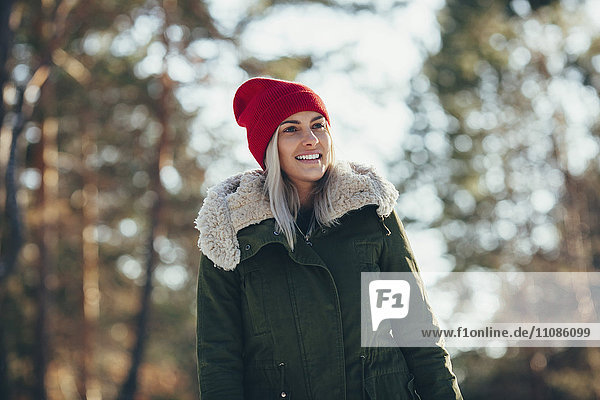 Low angle view of happy young woman wearing knit hat and jacket while looking away