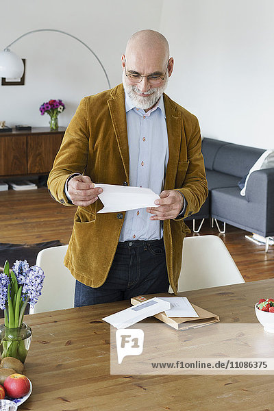 Erwachsener Mann liest Brief an Tisch zu Hause