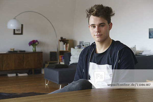 Portrait of teenage boy sitting by table at home
