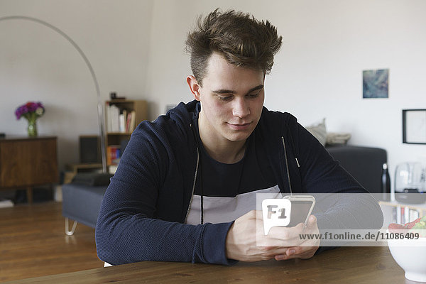 Teenager using smart phone on table at home