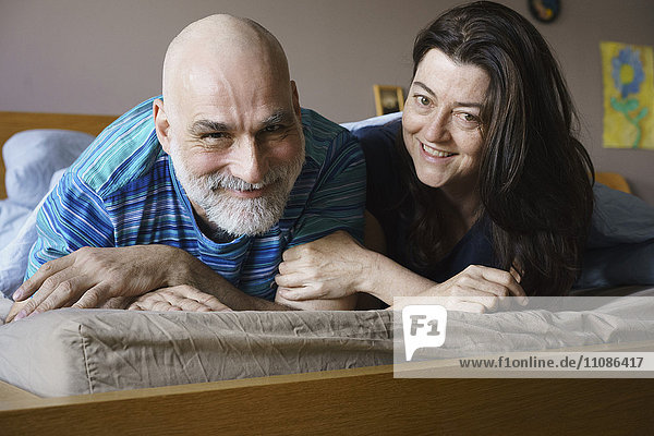 Porträt eines glücklichen  reifen Paares  das zu Hause auf dem Bett liegt.
