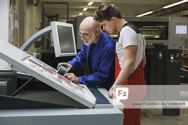 Reife Mitarbeiterin  die die Qualität des Ausdrucks mit Scanner an der Druckmaschine zeigt