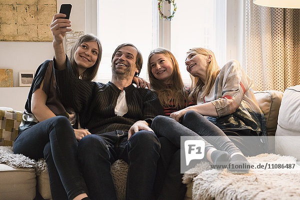 Glückliche vierköpfige Familie  die zu Hause über das Handy spricht