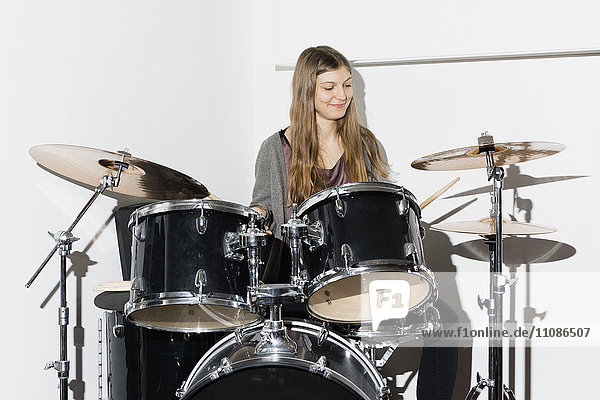 Junge Frau lächelt beim Schlagzeug spielen