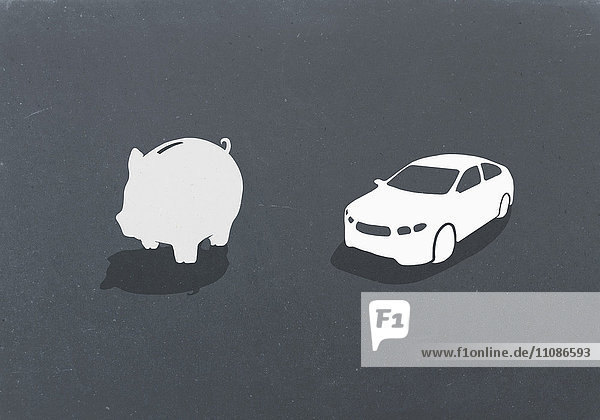 Sparschwein und Auto vor grauem Hintergrund