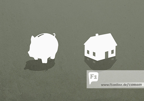 Sparschwein und Haus vor grauem Hintergrund