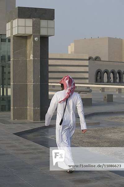 Rückansicht eines arabischen Mannes  der auf dem Boden gegen Gebäude geht.