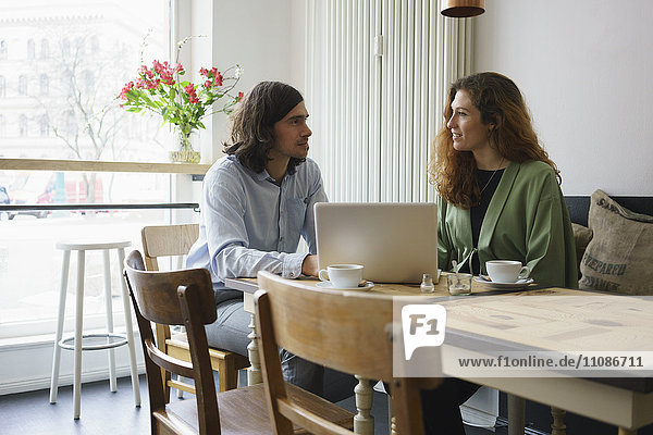 Freunde diskutieren bei der Benutzung des Laptops im Cafe