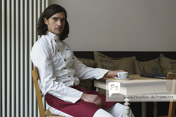 Portrait of confident chef having coffee at cafe