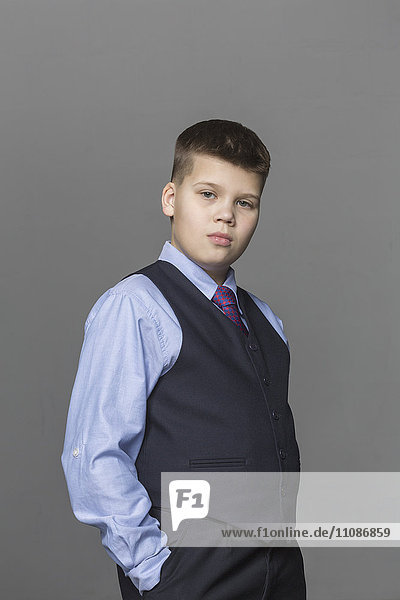 Portrait of confident boy standing against gray background