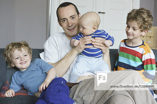 Porträt des lächelnden Vaters mit zu Hause sitzenden Kindern