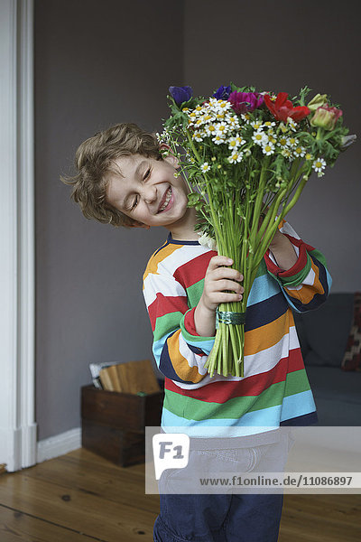 Fröhlicher Junge mit einem Blumenstrauß zu Hause