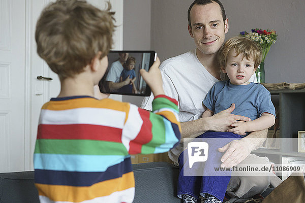 Junge fotografiert Familie durch digitales Tablett zu Hause