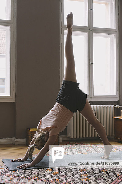 Young woman practicing yoga in living room