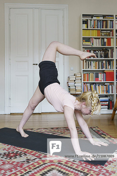 Junge Frau beim Yoga im Wohnzimmer zu Hause