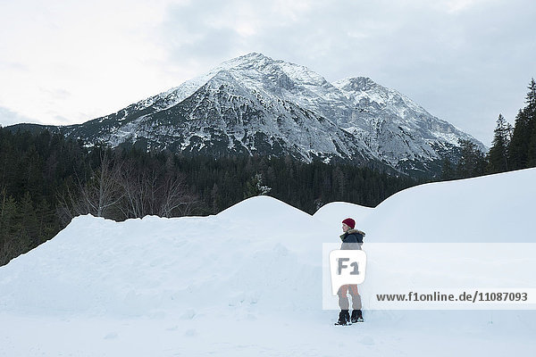 Frau steht auf schneebedecktem Feld gegen Berge