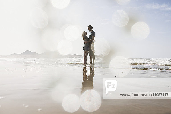 Volle Länge des romantischen Paares,  das sich am Strand umarmt.