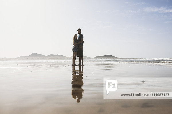Volle Länge des liebenden Paares  das sich an einem sonnigen Tag am Strand umarmt.