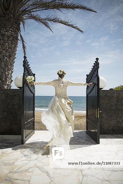 Rückansicht des sich öffnenden Tores der Braut auf dem Weg zum Strand