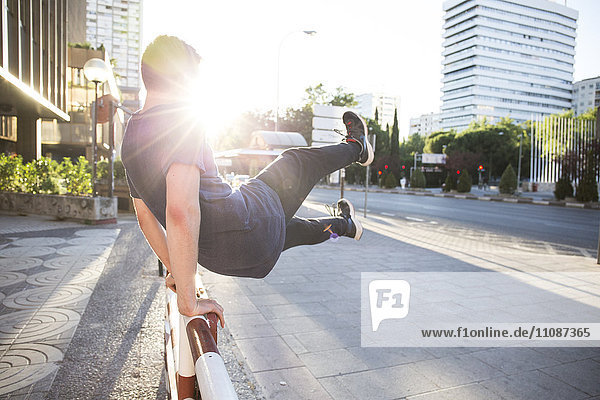 Spanien  Madrid  Mann beim Springen über einen Zaun in der Stadt während einer Parkour-Session