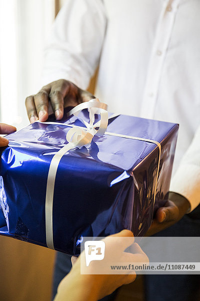 Close-up of man handing over Christmas present to woman