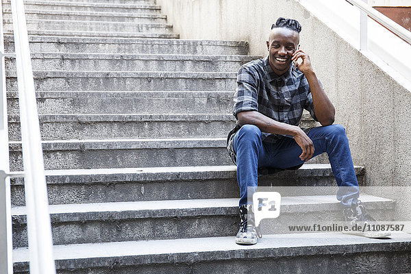 Young man sitting on stairs  using smart phone