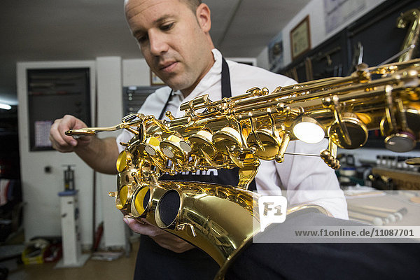 Instrument maker dismounting a saxophone during a repair